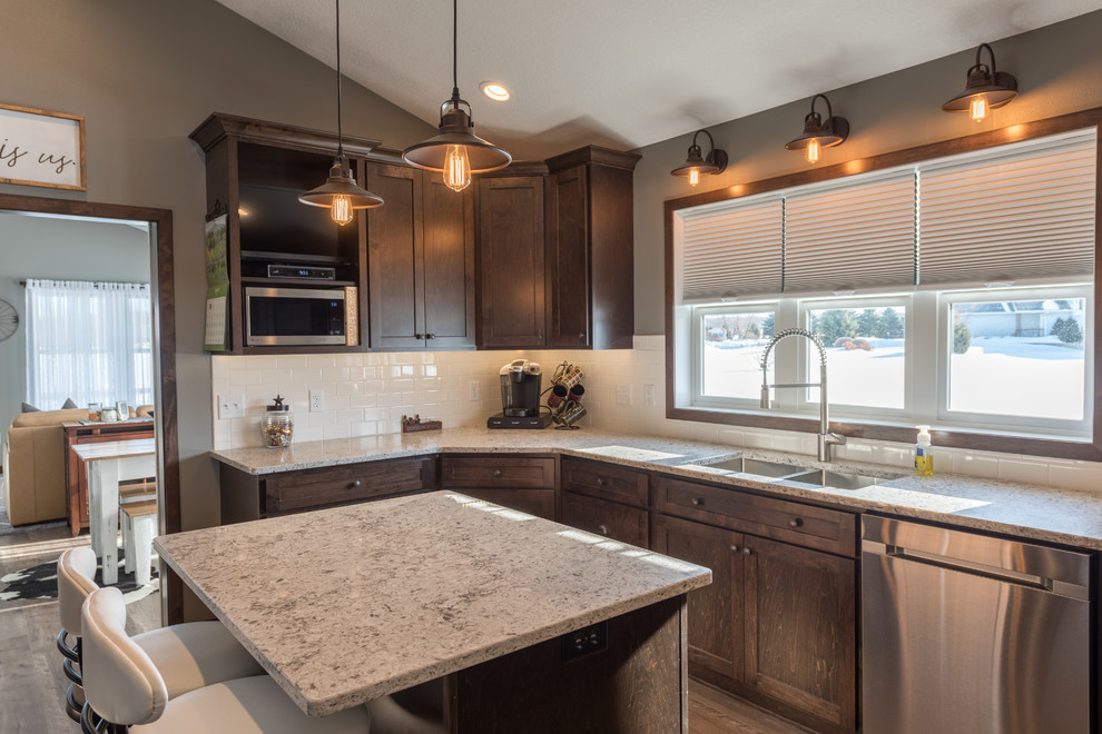 Inspiration for a large rustic u-shaped dark wood floor and brown floor enclosed kitchen remodel in Minneapolis with a double-bowl sink, shaker cabinets, dark wood cabinets, granite countertops, white backsplash, subway tile backsplash, stainless steel appliances and an island