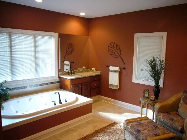 Design ideas for a bathroom in Grand Rapids with a drop-in sink, recessed-panel cabinets, dark wood cabinets, granite benchtops, a drop-in tub, ceramic tile, orange walls and ceramic floors.