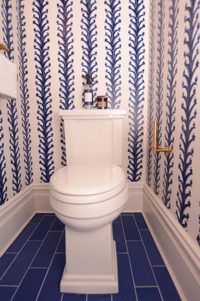 This is an example of a small transitional powder room in New York with a two-piece toilet, white walls, porcelain floors, a wall-mount sink and blue floor.