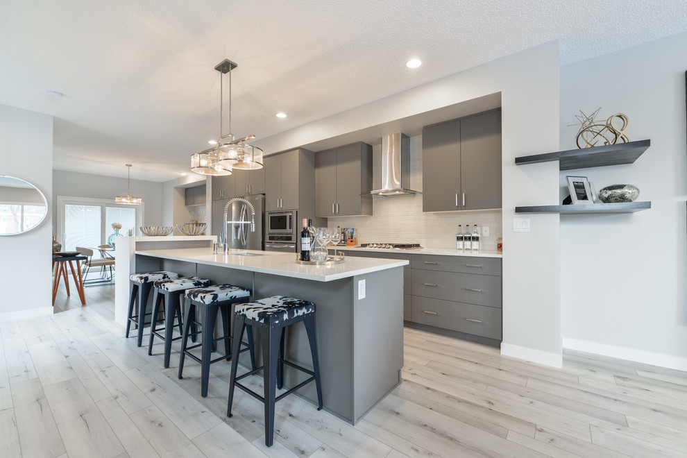 Mid-sized contemporary galley eat-in kitchen in Edmonton with an undermount sink, flat-panel cabinets, grey cabinets, quartzite benchtops, white splashback, ceramic splashback, stainless steel appliances, vinyl floors, with island, white floor and white benchtop.