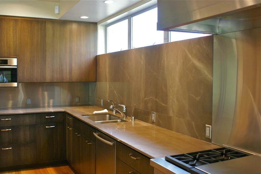 Photo of a contemporary kitchen in Seattle with a double-bowl sink, flat-panel cabinets, dark wood cabinets, stone slab splashback, stainless steel appliances and medium hardwood floors.
