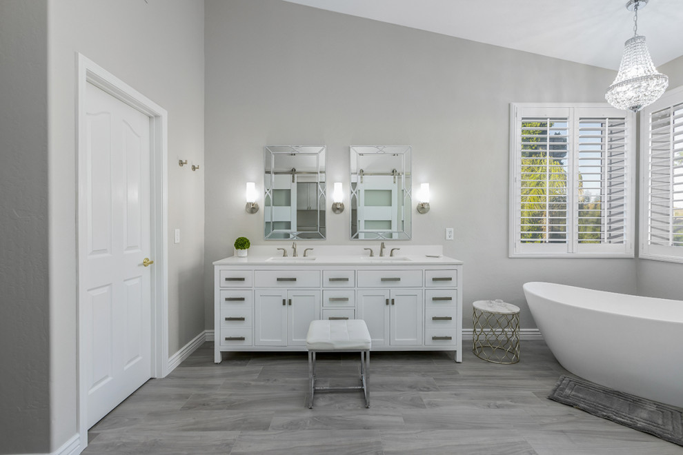 Idéer för ett mellanstort klassiskt vit en-suite badrum, med skåp i shakerstil, vita skåp, ett fristående badkar, vit kakel, porslinskakel, grå väggar, klinkergolv i porslin, ett undermonterad handfat, bänkskiva i kvarts och brunt golv