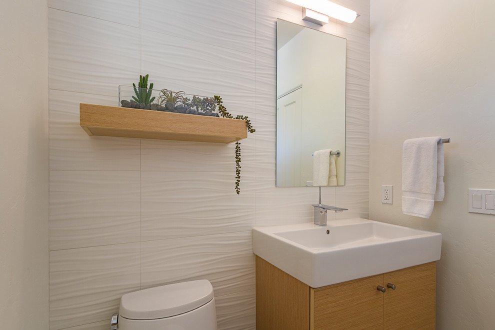 Inspiration for a small contemporary bathroom in Phoenix with flat-panel cabinets, light wood cabinets, a one-piece toilet, white tile, ceramic tile, white walls, porcelain floors, a trough sink, engineered quartz benchtops, grey floor and white benchtops.