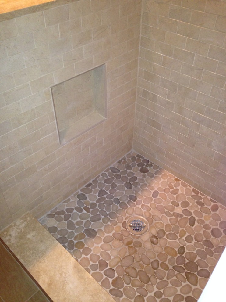 This is an example of a small master bathroom in New York with a corner shower, beige tile and stone tile.