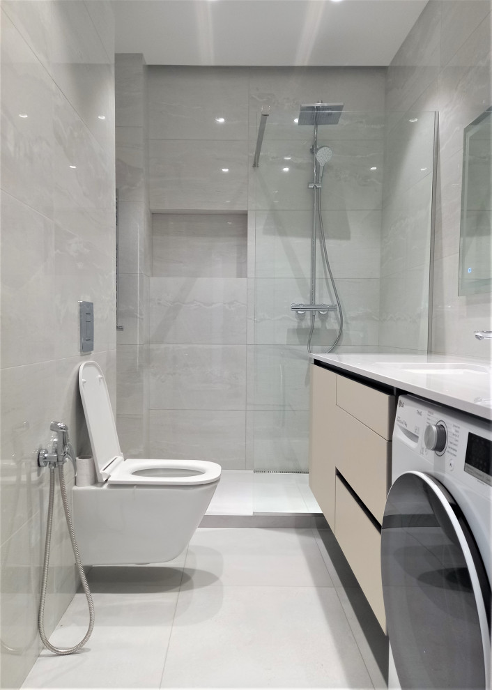 Exempel på ett mellanstort modernt vit vitt badrum med dusch, med släta luckor, beige skåp, våtrum, en vägghängd toalettstol, grå kakel, keramikplattor, grå väggar, klinkergolv i keramik, ett nedsänkt handfat, bänkskiva i akrylsten, grått golv och med dusch som är öppen