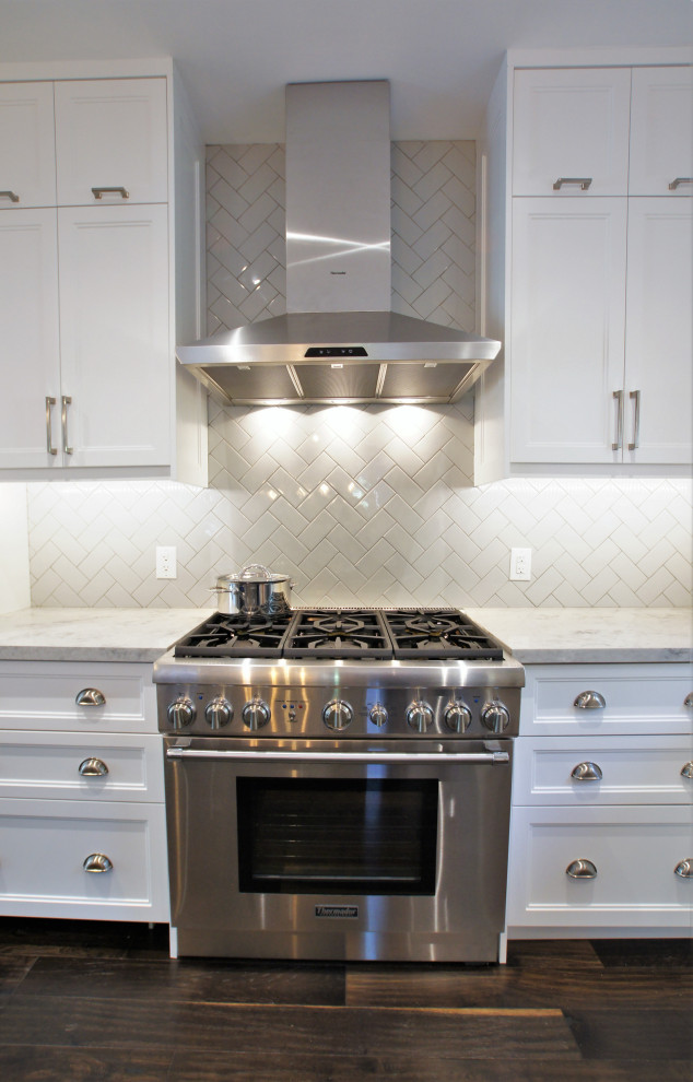 Eat-in kitchen - large transitional l-shaped dark wood floor and brown floor eat-in kitchen idea in Toronto with a farmhouse sink, shaker cabinets, white cabinets, quartz countertops, gray backsplash, subway tile backsplash, stainless steel appliances, an island and gray countertops