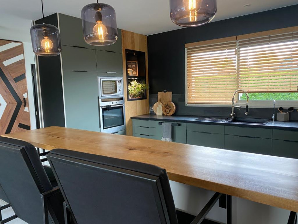 Photo of a mid-sized modern u-shaped eat-in kitchen in Other with an undermount sink, beaded inset cabinets, green cabinets, concrete benchtops, black splashback, stone slab splashback, stainless steel appliances, no island, grey floor and black benchtop.