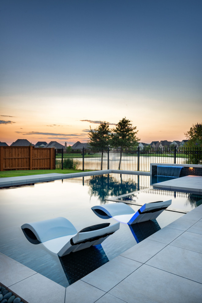 This is an example of a mid-sized modern backyard custom-shaped pool in Dallas with a water feature.