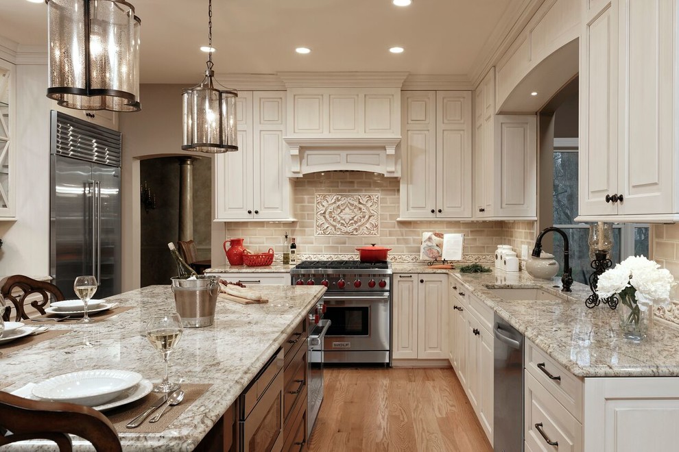This is an example of a large traditional u-shaped separate kitchen in DC Metro with an undermount sink, raised-panel cabinets, beige cabinets, beige splashback, medium hardwood floors, with island, granite benchtops, subway tile splashback, stainless steel appliances and brown floor.