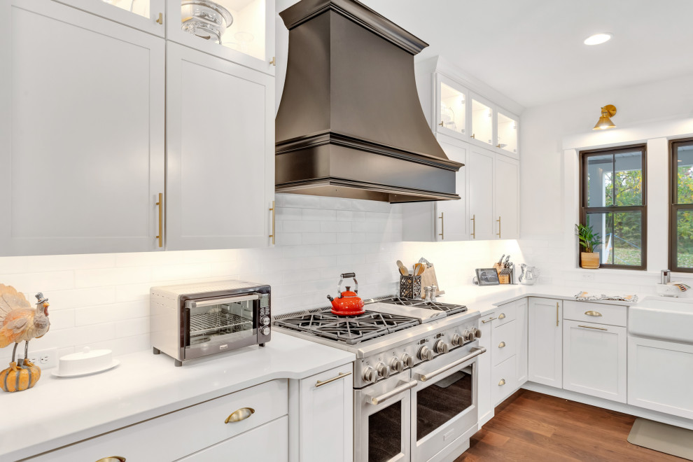 Large arts and crafts u-shaped eat-in kitchen in Other with a farmhouse sink, shaker cabinets, white cabinets, quartzite benchtops, white splashback, subway tile splashback, stainless steel appliances, medium hardwood floors, with island, black floor and yellow benchtop.