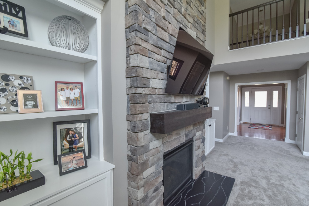 This is an example of a small classic games room in Cincinnati with beige walls, carpet, a standard fireplace, a stone fireplace surround, a wall mounted tv and beige floors.