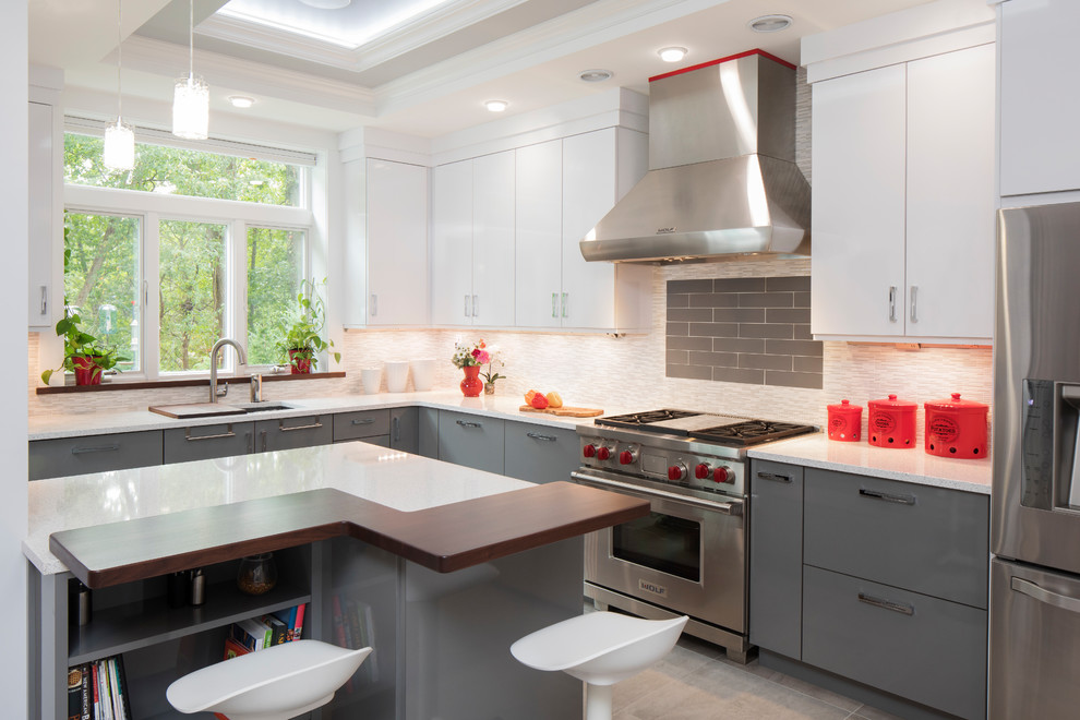 This is an example of a contemporary l-shaped kitchen in New York with an undermount sink, flat-panel cabinets, grey cabinets, multi-coloured splashback, matchstick tile splashback, stainless steel appliances and with island.