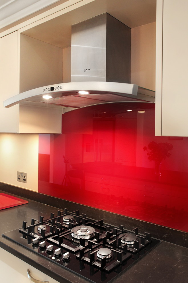 Photo of a large contemporary u-shaped kitchen/diner in Buckinghamshire with flat-panel cabinets, beige cabinets, quartz worktops, red splashback, glass sheet splashback, porcelain flooring, an island, a submerged sink and stainless steel appliances.