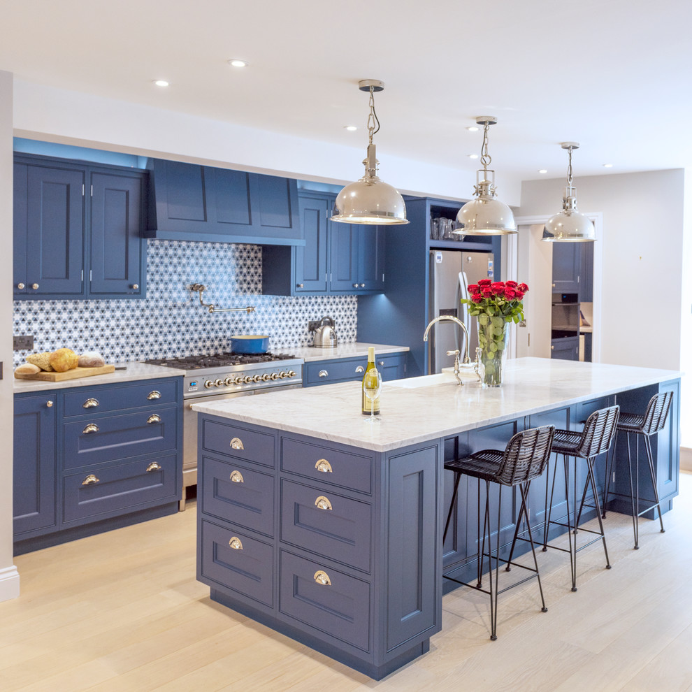 Design ideas for a large modern galley open plan kitchen in Other with a farmhouse sink, recessed-panel cabinets, blue cabinets, marble benchtops, multi-coloured splashback, stainless steel appliances, light hardwood floors, with island, white floor and white benchtop.