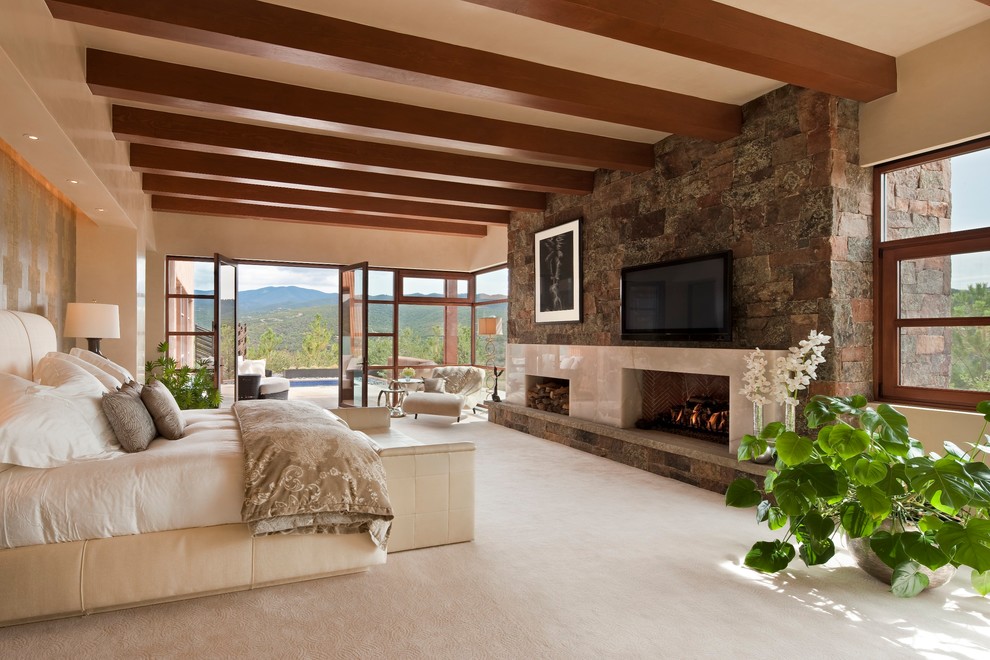 Inspiration pour une très grande chambre sud-ouest américain avec un mur beige, une cheminée standard et un manteau de cheminée en pierre.