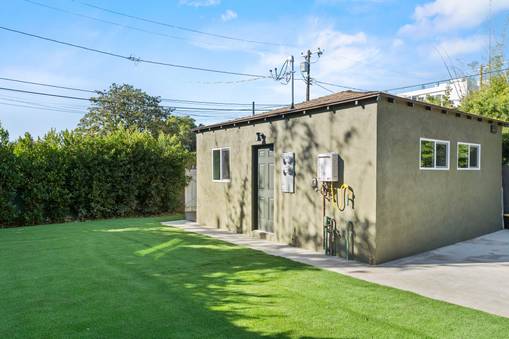 This is an example of a mid-sized modern one-storey green exterior in Los Angeles with painted brick siding, a flat roof, a shingle roof, a grey roof and shingle siding.