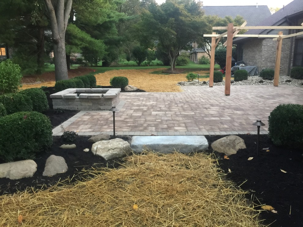 This is an example of a mid-sized traditional backyard patio in Other with a fire feature, concrete pavers and a pergola.