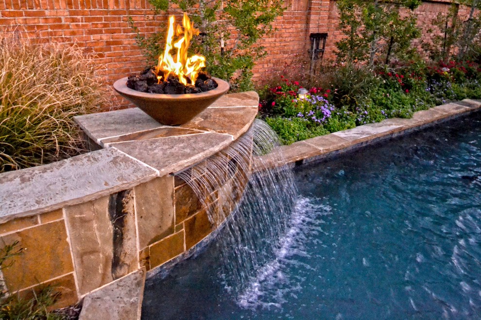 This is an example of a small contemporary backyard custom-shaped pool in Dallas with a water feature and stamped concrete.