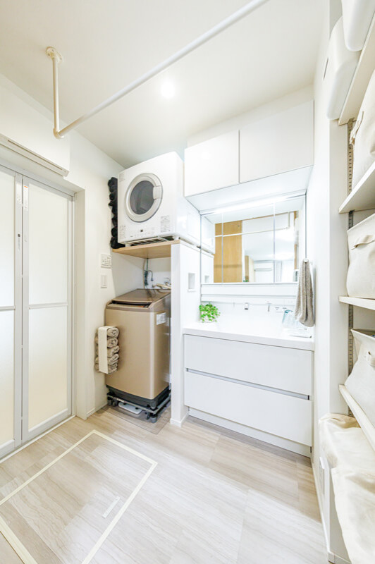 Design ideas for a mid-sized modern u-shaped utility room in Tokyo Suburbs with an undermount sink, open cabinets, white cabinets, white walls, light hardwood floors, a stacked washer and dryer, beige floor, white benchtop, wallpaper and wallpaper.