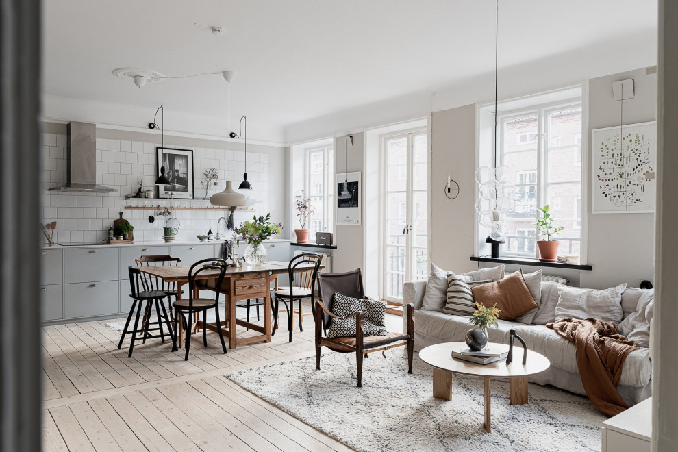 Foto de salón abierto escandinavo sin chimenea y televisor con paredes beige y suelo de madera clara