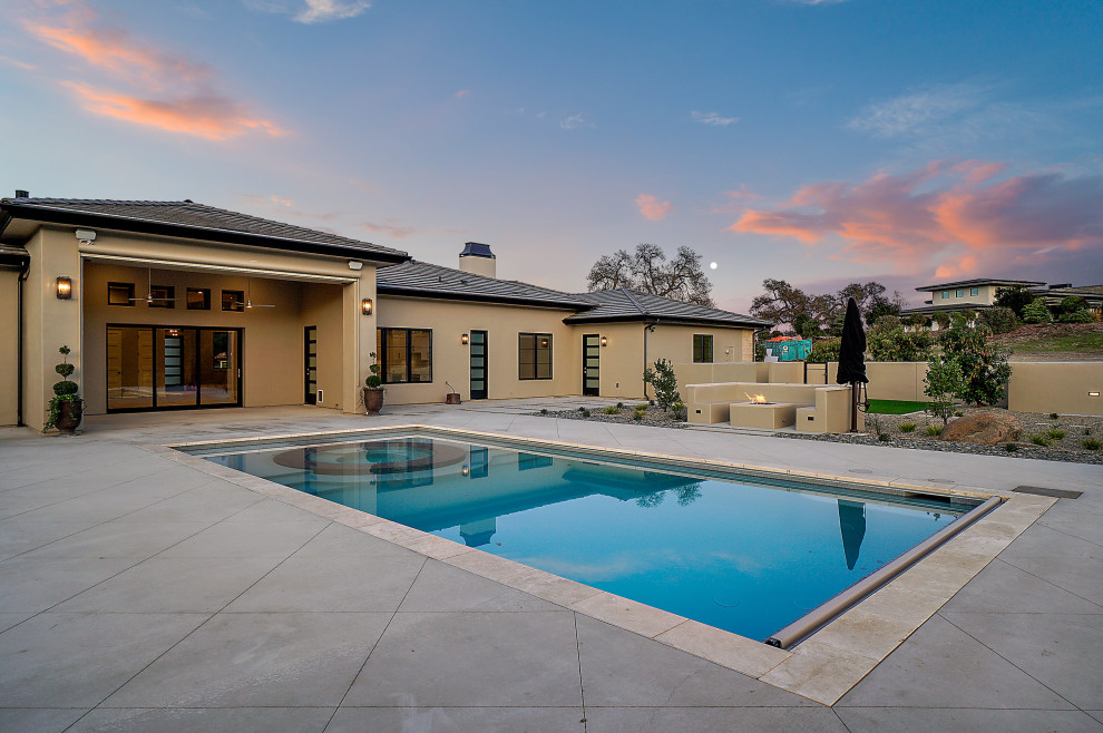 Large modern back rectangular natural swimming pool in San Luis Obispo with with pool landscaping and concrete slabs.