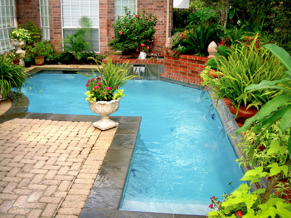 Small traditional backyard l-shaped pool in Houston with a water feature and natural stone pavers.