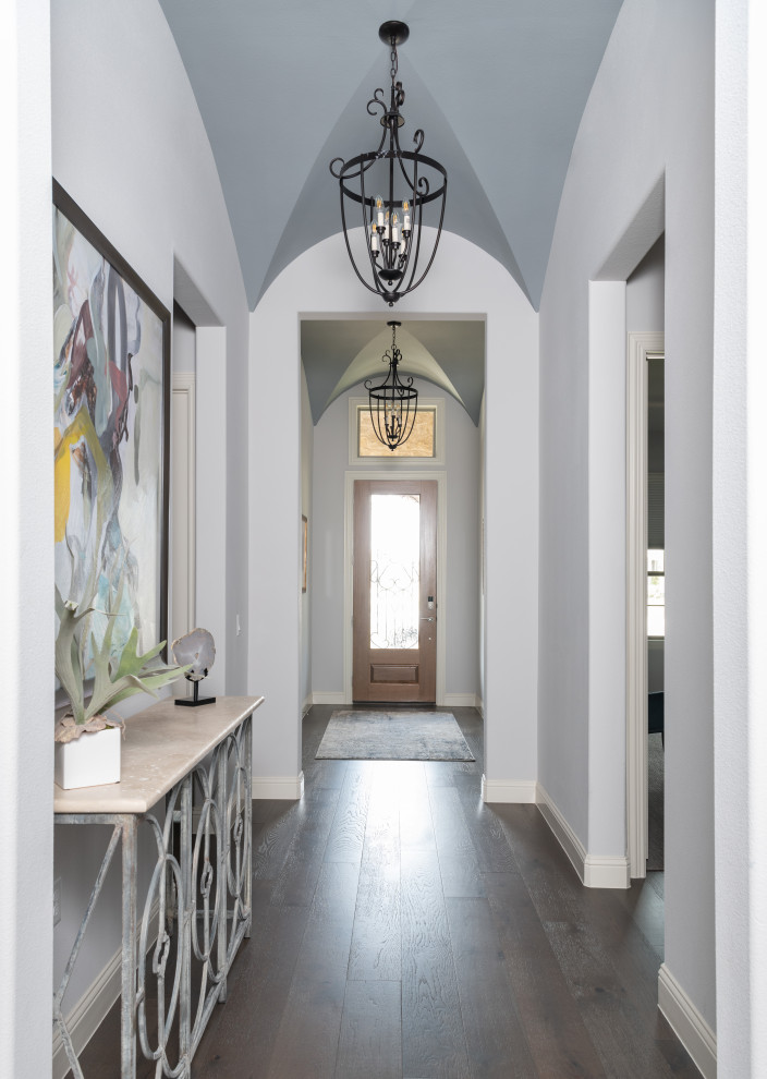 This is an example of a transitional entry hall in Dallas with white walls, dark hardwood floors, a single front door, a glass front door, brown floor and vaulted.