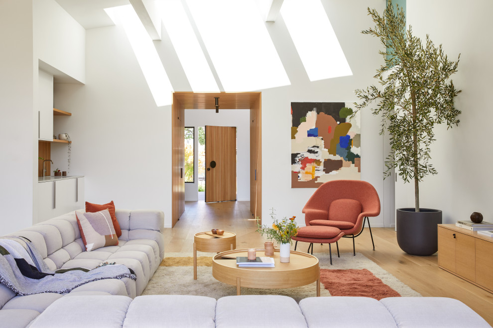 Immagine di un grande soggiorno minimalista aperto con angolo bar, pareti bianche, parquet chiaro, nessun camino, TV a parete, pavimento marrone e travi a vista