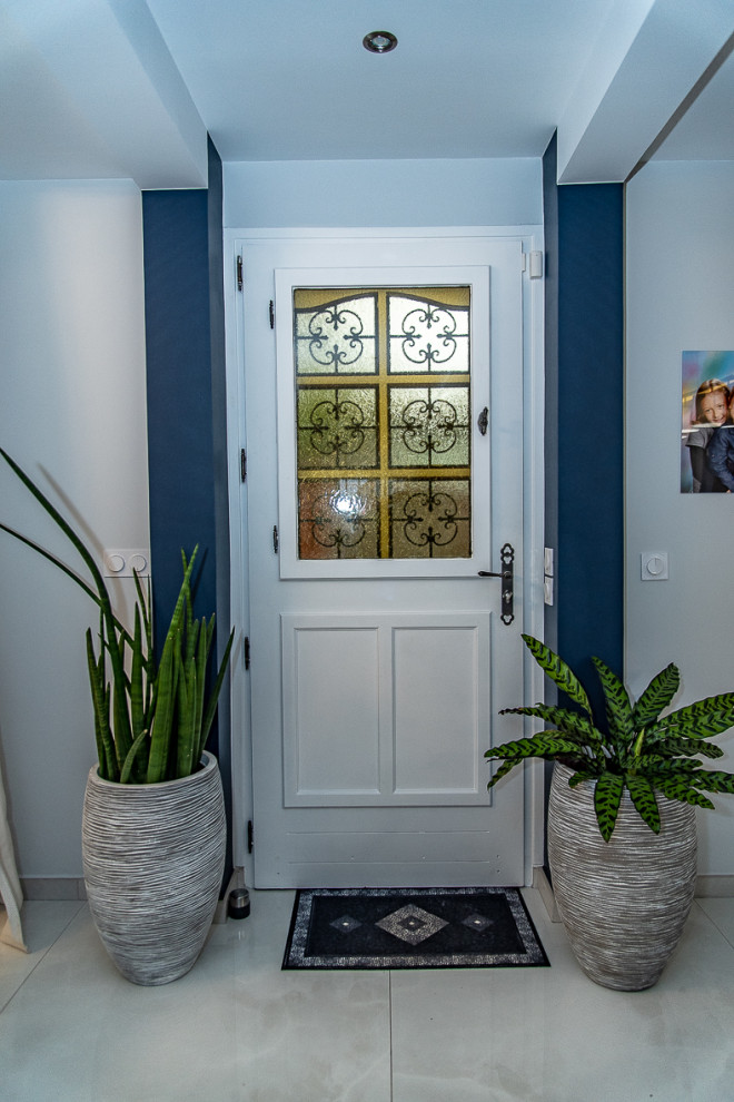 Cette photo montre une porte d'entrée tendance de taille moyenne avec un mur bleu, une porte simple, un sol gris et poutres apparentes.
