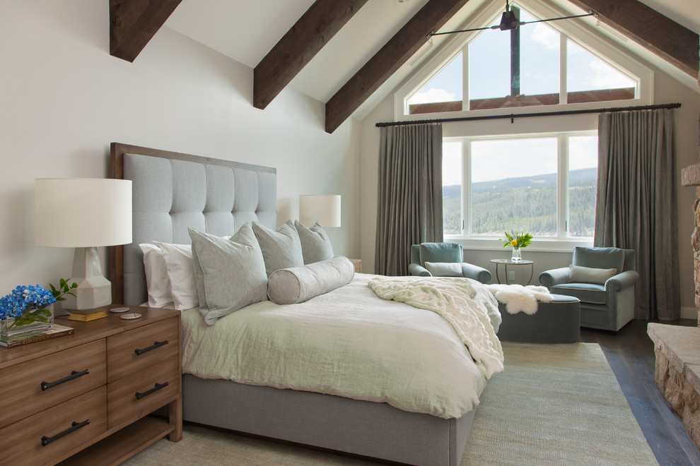 This is an example of a transitional bedroom in Other with white walls, dark hardwood floors, a standard fireplace, a stone fireplace surround and brown floor.
