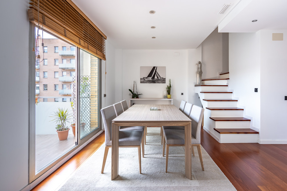 Design ideas for a mid-sized scandinavian open plan dining in Barcelona with white walls, medium hardwood floors, brown floor and no fireplace.