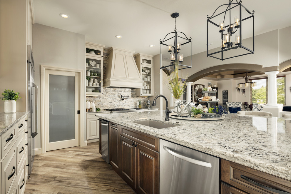 Example of a large transitional l-shaped porcelain tile and brown floor eat-in kitchen design in Orlando with an undermount sink, raised-panel cabinets, beige cabinets, quartz countertops, multicolored backsplash, travertine backsplash, stainless steel appliances, an island and multicolored countertops