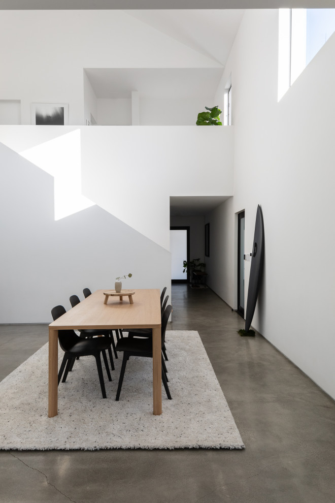 Small contemporary kitchen/dining combo in Los Angeles with white walls, concrete floors, grey floor, no fireplace and vaulted.