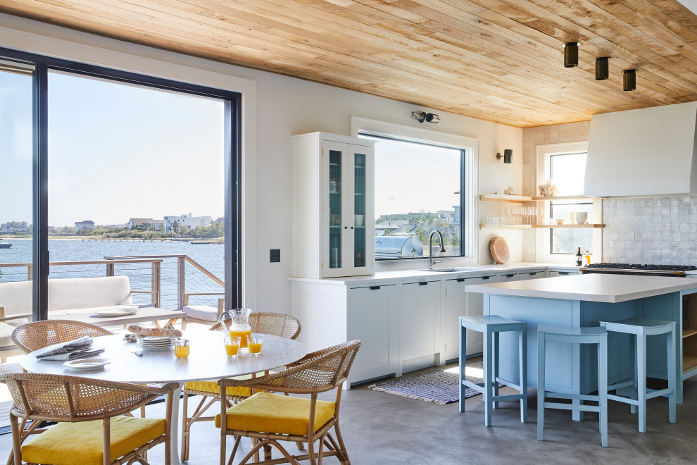 Идея дизайна: п-образная кухня в морском стиле с фасадами в стиле шейкер, белым фартуком, фартуком из терракотовой плитки, бетонным полом, островом, серым полом, белой столешницей и деревянным потолком
