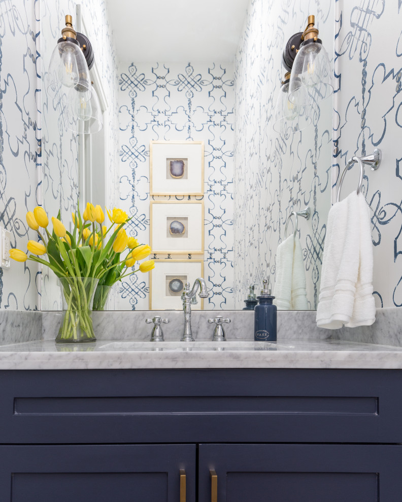 This is an example of a mid-sized transitional powder room in Houston with shaker cabinets, blue cabinets, multi-coloured walls, an undermount sink, grey benchtops, a built-in vanity and wallpaper.