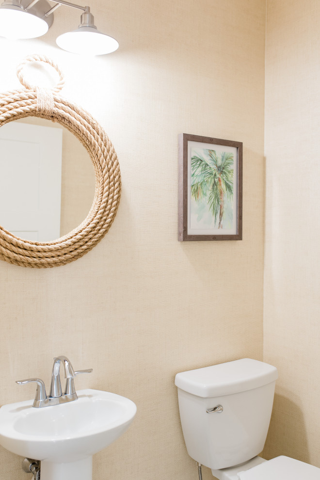 This is an example of a mid-sized beach style powder room in Other with white cabinets, a one-piece toilet, porcelain floors, a pedestal sink, white floor, white benchtops, a freestanding vanity, timber and wallpaper.