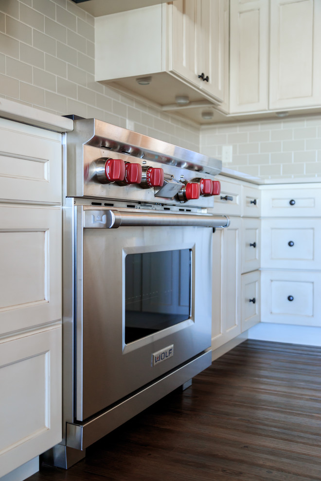 Kitchen - transitional l-shaped vinyl floor kitchen idea in Minneapolis with an undermount sink, raised-panel cabinets, white cabinets, quartz countertops, beige backsplash, ceramic backsplash, paneled appliances and an island