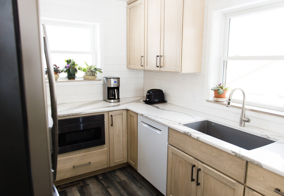 Enclosed kitchen - mid-sized transitional u-shaped vinyl floor and brown floor enclosed kitchen idea with an undermount sink, flat-panel cabinets, beige cabinets, quartz countertops, white backsplash, subway tile backsplash, black appliances, a peninsula and white countertops