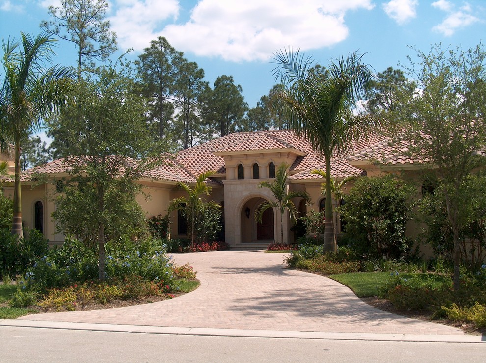 Photo of a large mediterranean two-storey beige house exterior in Miami with mixed siding, a gable roof and a tile roof.