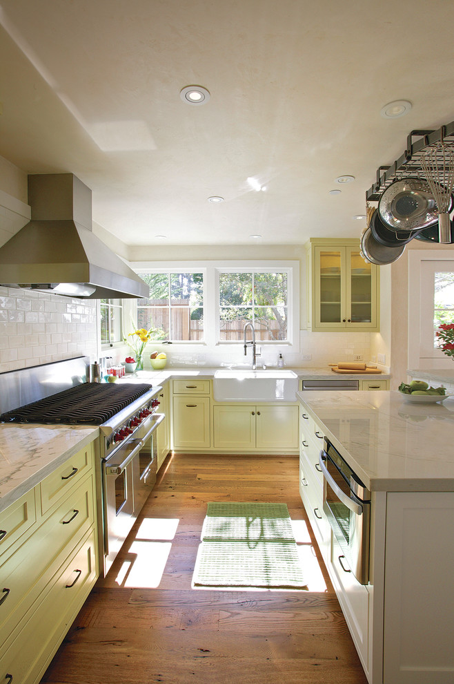 Design ideas for a country kitchen in Other with a farmhouse sink, shaker cabinets, yellow cabinets, white splashback, subway tile splashback and stainless steel appliances.