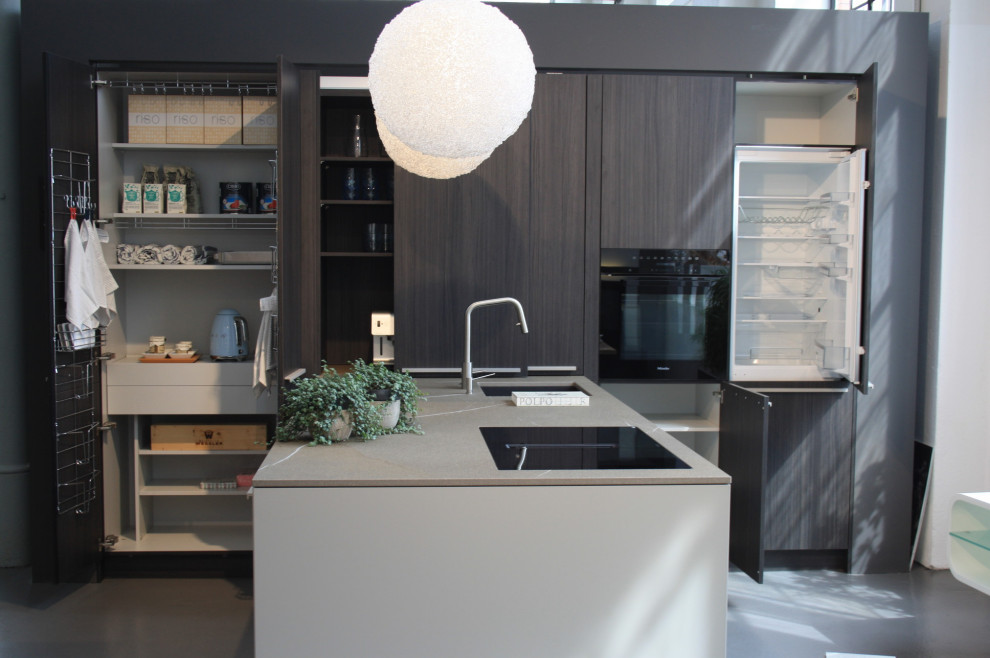 This is an example of a large contemporary galley open plan kitchen in Dresden with flat-panel cabinets, dark wood cabinets, black appliances and a peninsula.