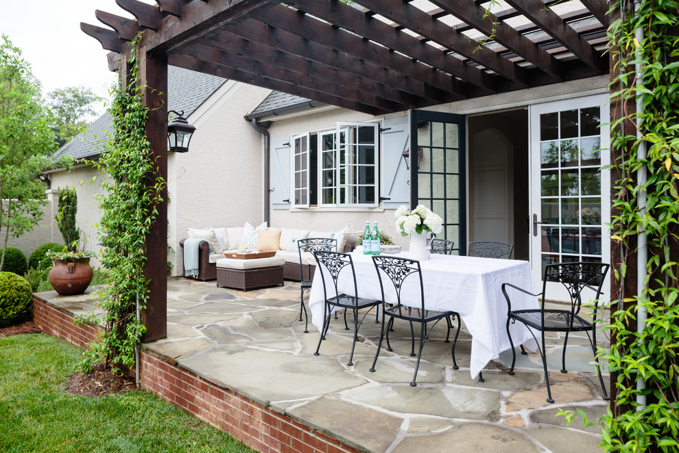This is an example of a country backyard patio in Other with a pergola.