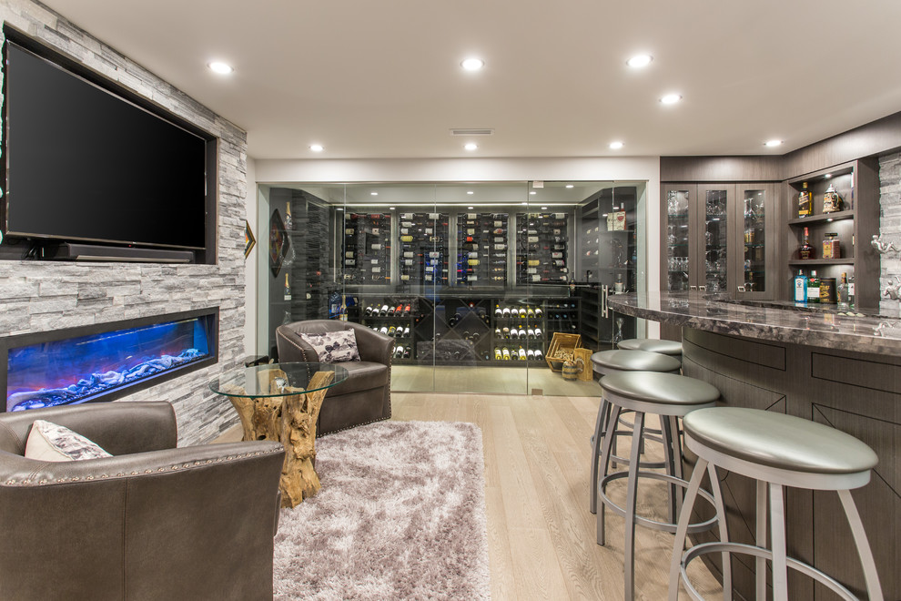 Inspiration for a large transitional u-shaped seated home bar in Vancouver with an undermount sink, brown cabinets, marble benchtops, grey splashback, stone tile splashback, medium hardwood floors, beige floor and black benchtop.