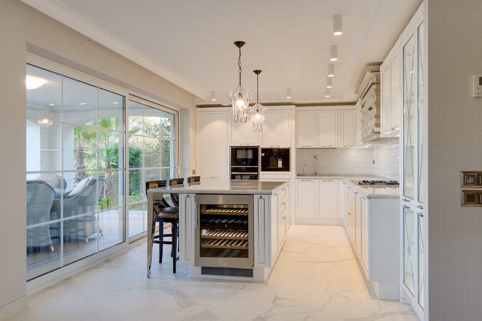 Inspiration for a contemporary l-shaped separate kitchen with white cabinets, white splashback, subway tile splashback, black appliances, with island, white floor, an undermount sink, shaker cabinets and grey benchtop.
