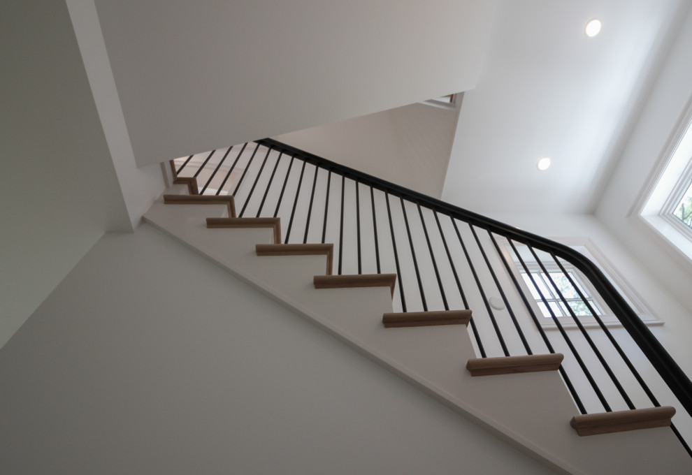 Идея дизайна: большая п-образная лестница в стиле модернизм с деревянными ступенями, крашенными деревянными подступенками, перилами из смешанных материалов и панелями на стенах