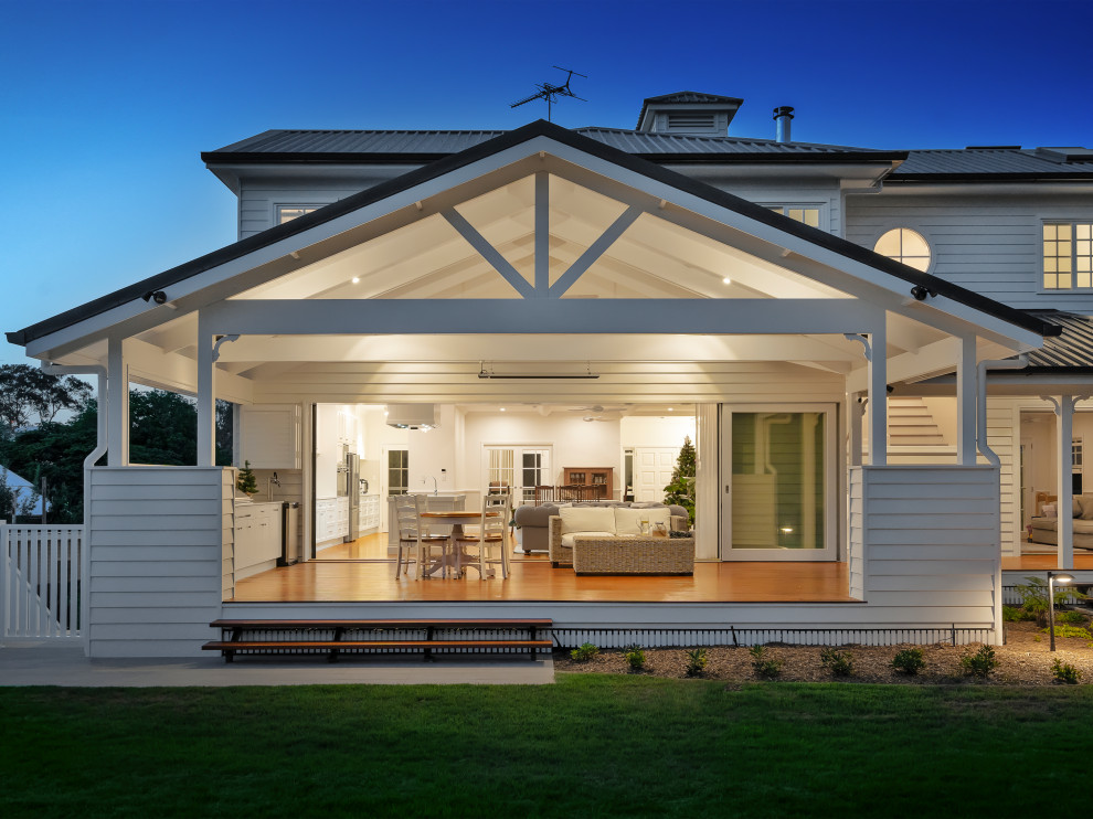 Large traditional backyard and ground level deck in Brisbane with an outdoor kitchen, a roof extension and wood railing.