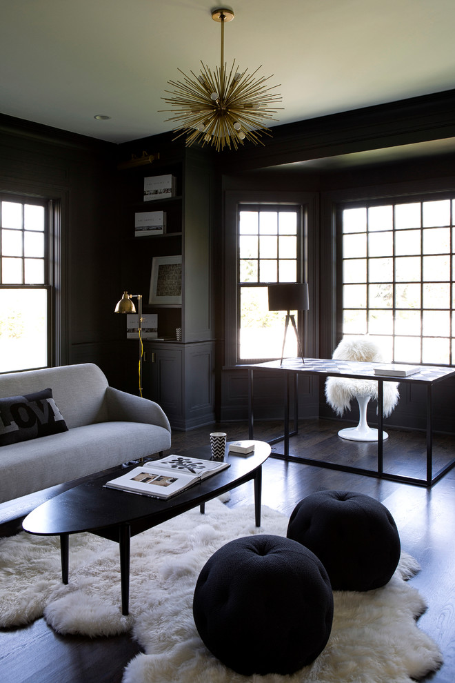 This is an example of a transitional study room in New York with grey walls, dark hardwood floors, a standard fireplace and a freestanding desk.