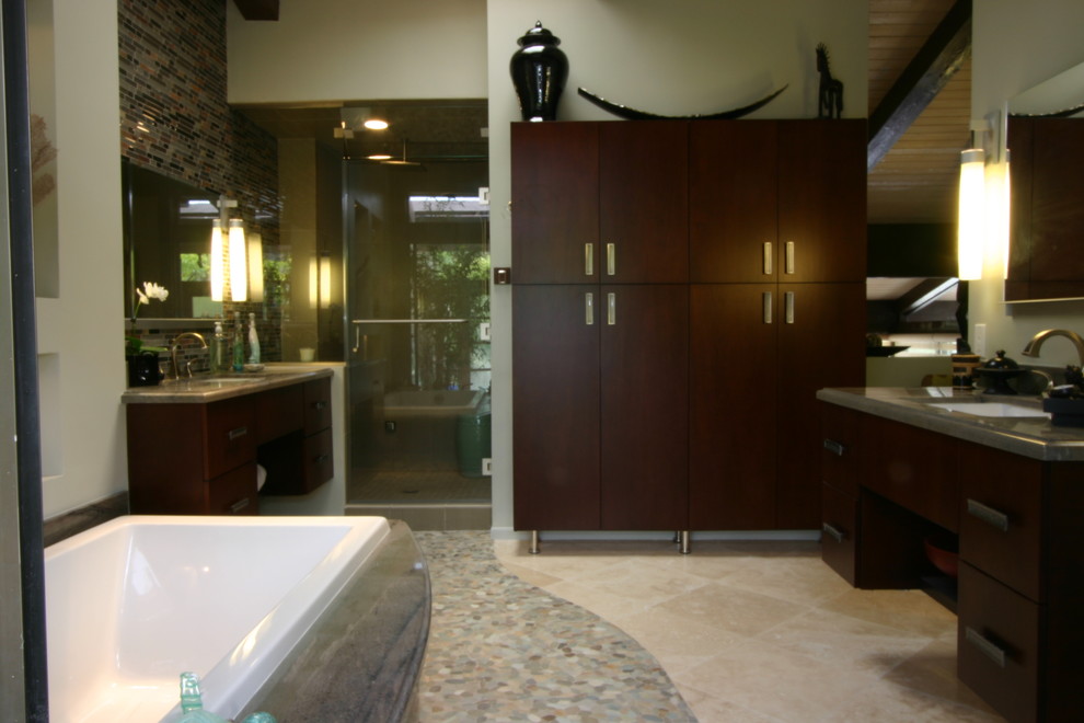 Photo of a large asian master wet room bathroom in Los Angeles with flat-panel cabinets, dark wood cabinets, a drop-in tub, a two-piece toilet, multi-coloured tile, beige walls, pebble tile floors, an undermount sink, granite benchtops and a hinged shower door.