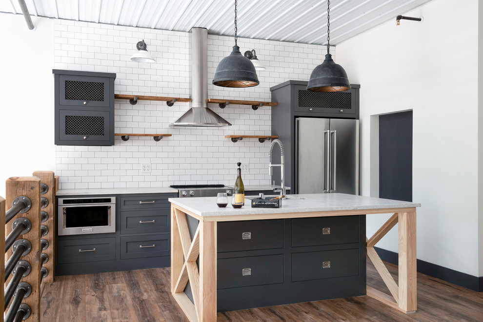 Photo of an industrial eat-in kitchen in Minneapolis with open cabinets, medium wood cabinets, white splashback, stainless steel appliances, with island, brown floor and yellow benchtop.