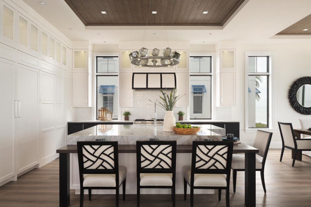 Mid-sized beach style eat-in kitchen in Miami with shaker cabinets, white cabinets, granite benchtops, white splashback, subway tile splashback, with island, brown floor, an undermount sink, stainless steel appliances, dark hardwood floors, white benchtop, recessed and wood.
